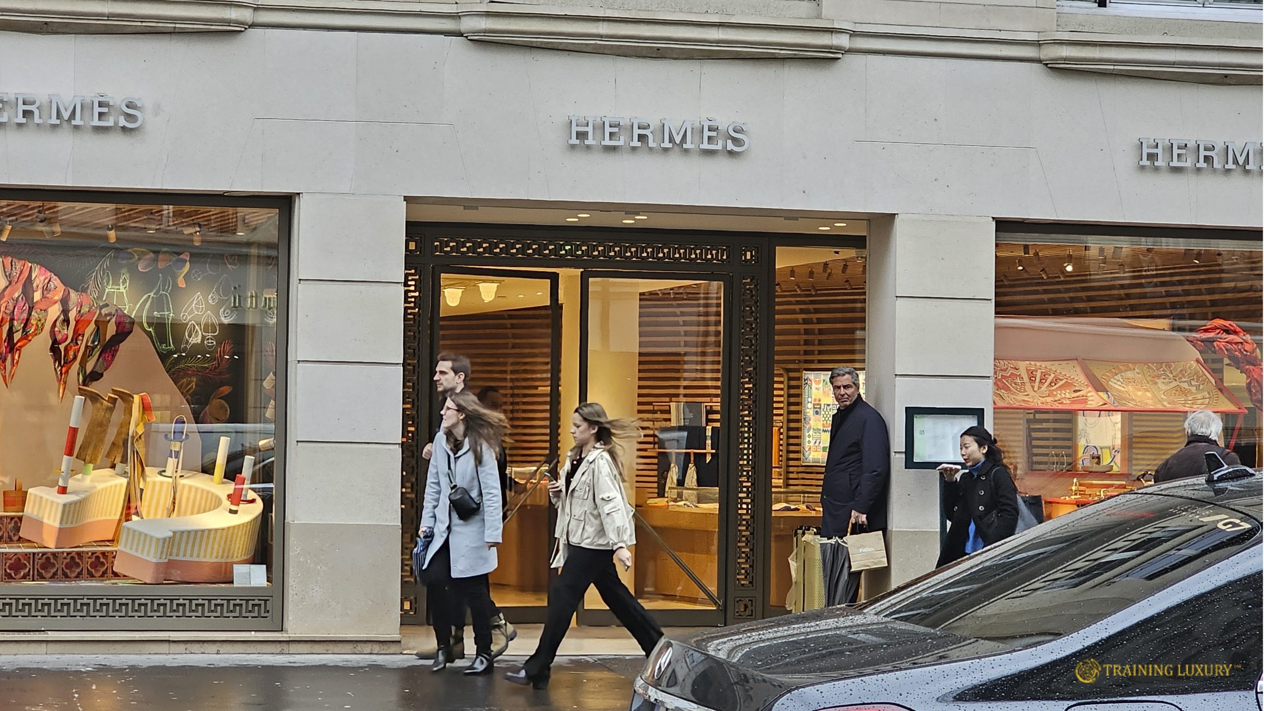 Luxury retail storefront with people entering and leaving a Hermès boutique, illustrating modern luxury shopping dynamics and customer experience